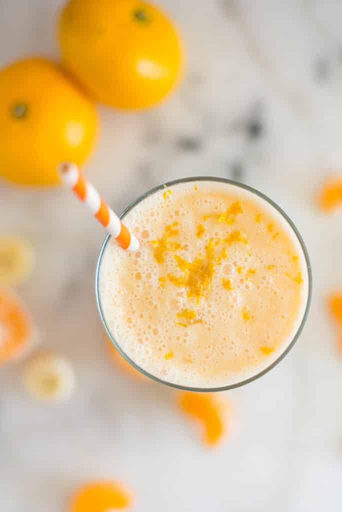 A glass of Orange Dreamsicle Smoothie with mandarin oranges, a banana, greek yogurt, vanilla extract, raw honey and almond milk topped with orange zest.