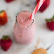 A glass bottle overflowing with the PB&J Smoothie with strawberries, flaxseed meal, peanut butter, oats and almond milk.