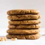 Peanut butter paleo cookies stacked on top of each other, setting next to raw peanuts.
