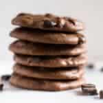 Dark Chocolate Chunk paleo cookies stacked on top of each other, setting next to dark chocolate morsels.