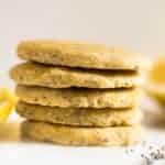 Chia seed lemon paleo cookies stacked on top of each other, setting next to fresh lemon and chia seeds.
