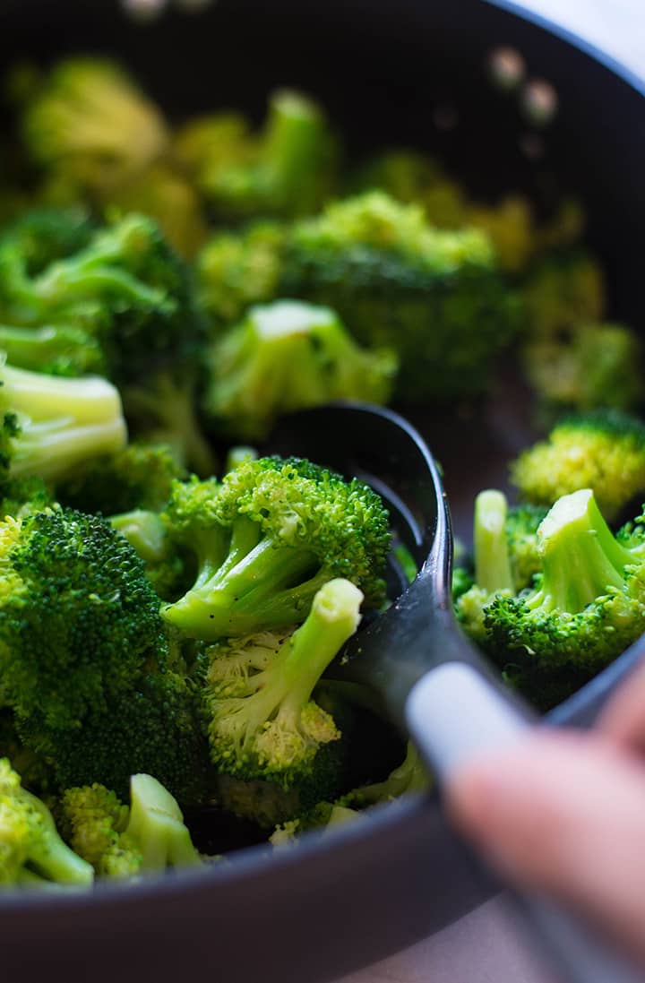 Sautéed broccoli in a large skillet that will be used in the meal prep chicken recipe.
