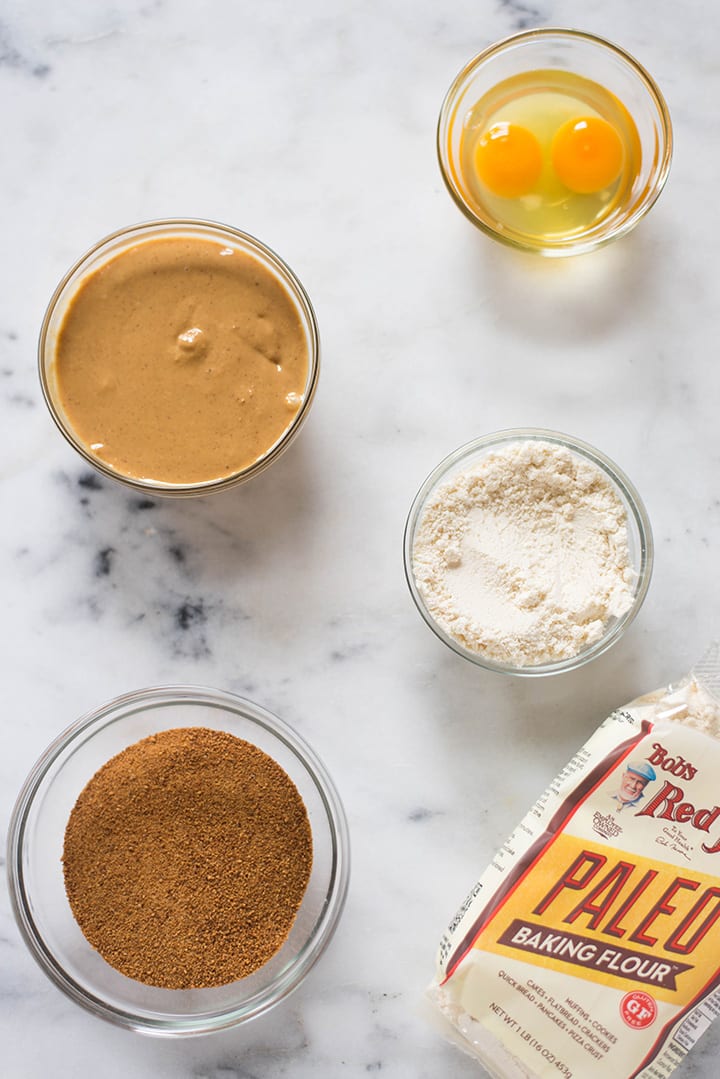 Ingredients needed to make protein peanut butter paleo coolkies, which include peanut butter, coconut sugar, eggs, and paleo baking flour.