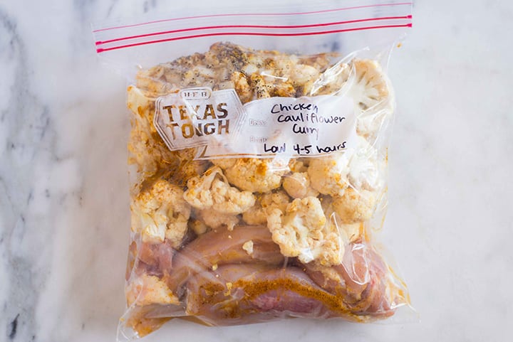 Ziploc bag filled with uncooked ingredients for slow cooker chicken cauliflower curry.