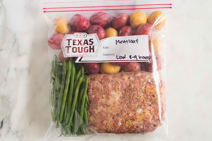 Ziploc bag filled with meatloaf, green beans, and potatoes, ready to be frozen and then added to a crock pot for a slow cooker freezer meal.