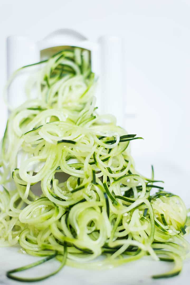 Close up image of zucchini noodles just prepped and coming out of the spiralizer.