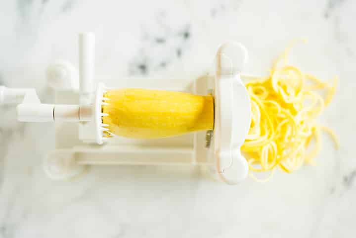 Overhead view of a yellow squash being spiralized to show how to spiralize yellow squash.
