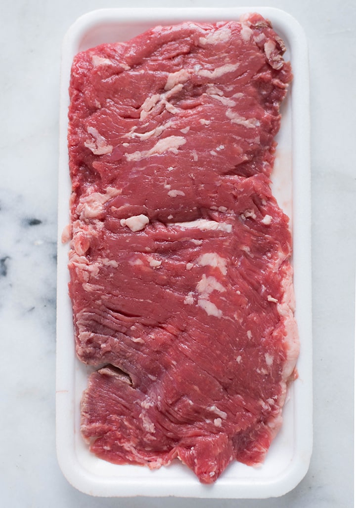 Overhead view of a raw piece of skirt steak, shown as an example of what type of steak is good for marinades since it has tough fibers that are broken down with the marinade.