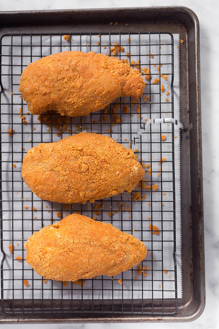 The boneless skinless chicken breast for the Nashville Hot Chicken that has been coated and is not on the baking sheet, ready to be placed into the oven and baked.