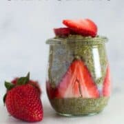 Strawberry matcha chia pudding recipe in a jar that has sliced strawberries pressed against the inside of the jar which is then filled with the matcha chia pudding recipe and then topped off with more sliced strawberries.