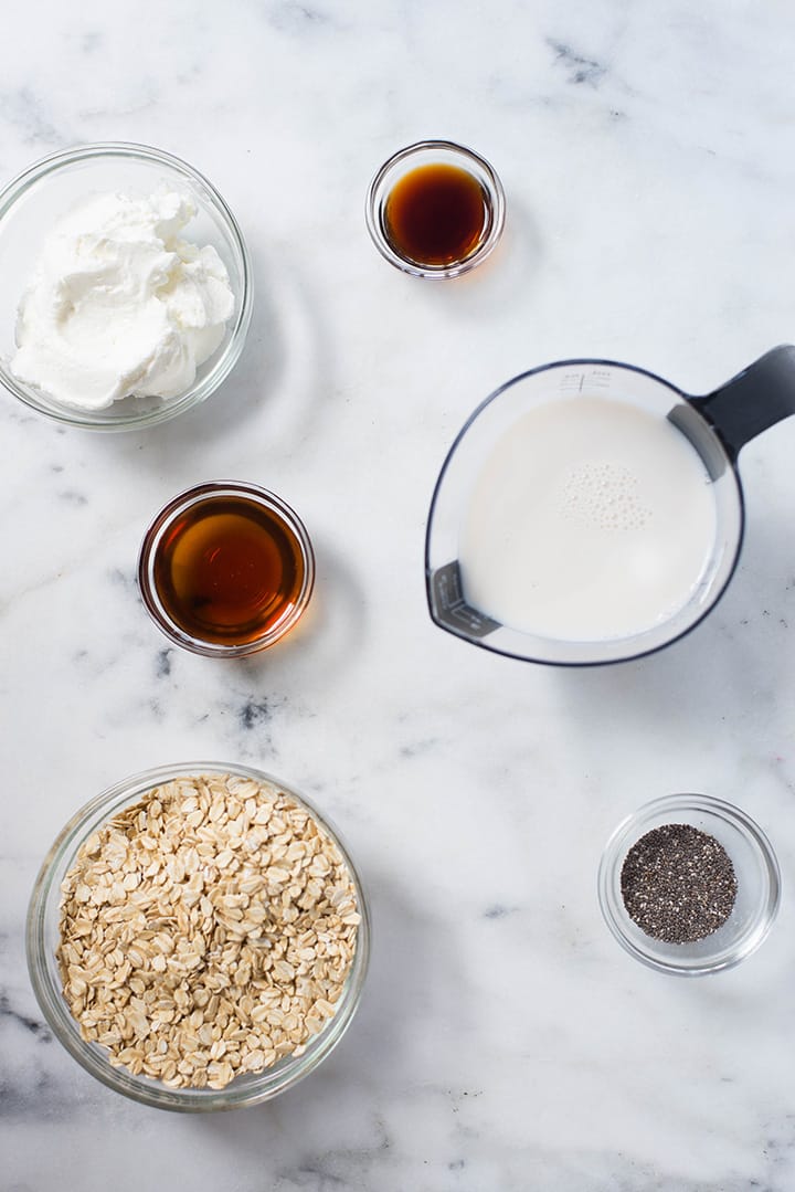 Ingredients separated for the 6 Best Overnight Oats recipe, including rolled oats, almond milk, chia seeds, plain Greek yogurt, vanilla, and pure maple syrup.