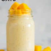 Horizontal view of a jar with Mango Overnight Oats with rolled oats, mango, banana, chia seeds, pure maple syrup, vanilla, plain greek yogurt and almond milk, topped with diced fresh mango