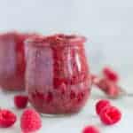 A side image of a glass jar filled with Homemade Raspberry Chia Jam made from fresh raspberries, chia seeds, and raw honey.