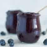 A side image of a glass jar filled with Homemade Blueberry Chia Jam made from fresh blueberries, chia seeds, and raw honey.