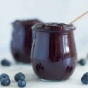 A side image of a glass jar filled with Homemade Blueberry Chia Jam made from fresh blueberries, chia seeds, and raw honey.