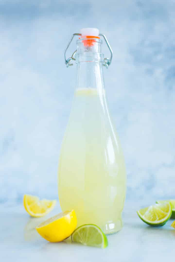 A side image of a sealed glass bottle with Caffeine-free Homemade Lemon Lime Soda made with freshly squeezed lemon juice, freshly squeezed lime juice, raw honey simple syrup and seltzer water.