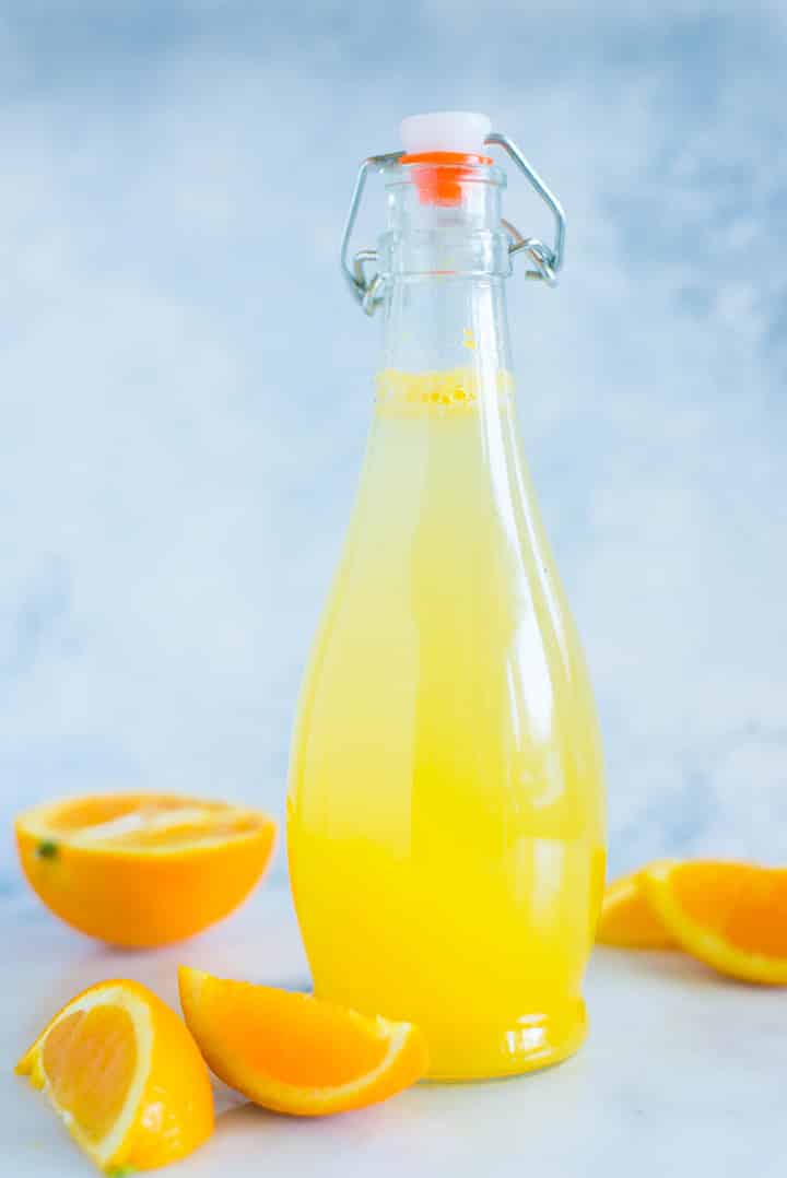 A side image of a sealed glass bottle with Caffeine-free Homemade Orange Soda made with freshly squeezed orange juice raw honey simple syrup and seltzer water.