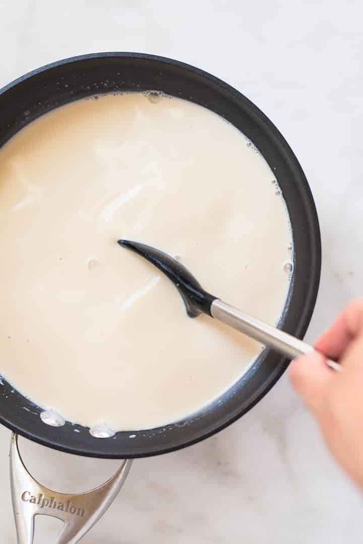 An overhead image of a spoon stirring the homemade coffee creamer made with homemade condensed milk, almond milk, pure maple syrup, vanilla extract and arrowroot starch.