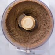 An overhead image of a food processor with Black Bean Hummus made from black beans, jalapeno pepper, cilantro, garlic, sea salt, extra virgin olive oil, paprika, cumin and lime juice.