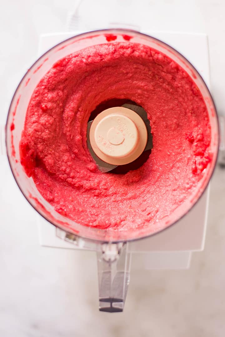 An overhead image of a food processor with raspberry puree made of fresh raspberries for the Raspberry Sorbet.
