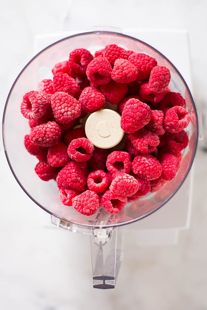 An overhead image of a food processor with whole fresh raspberries for the Raspberry Sorbet