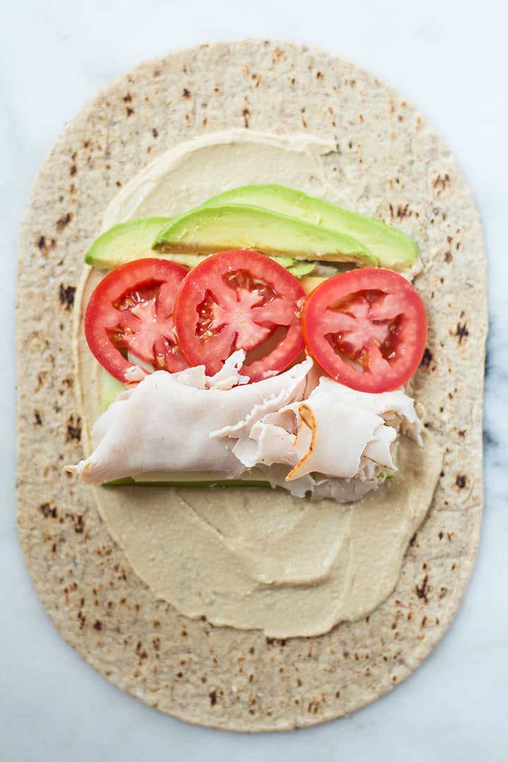 Avocado Turkey Hummus Wrap laid out and ready to roll up into a wrap, showing how to place everything onto the wrap.