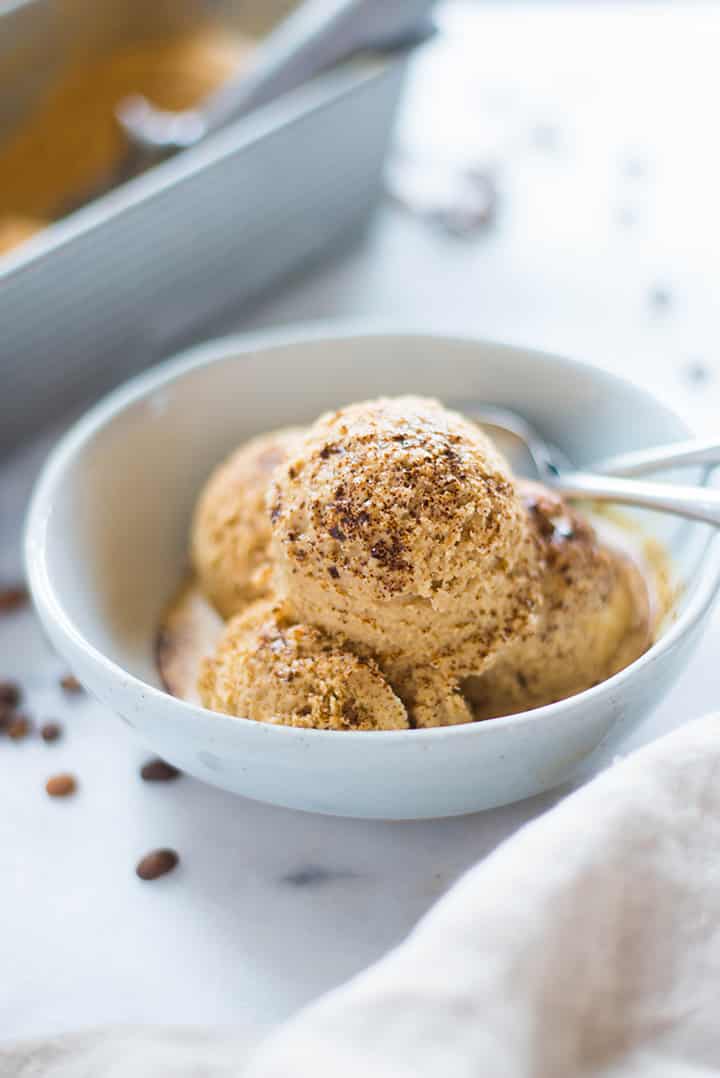 A side image of a serving of Coffee Ice Cream in an ice cream bowl, made with full fat coconut milk, pure maple syrup, brewed and chilled strong coffee, instant coffee and vanilla extract, sprinkled with instant coffee.