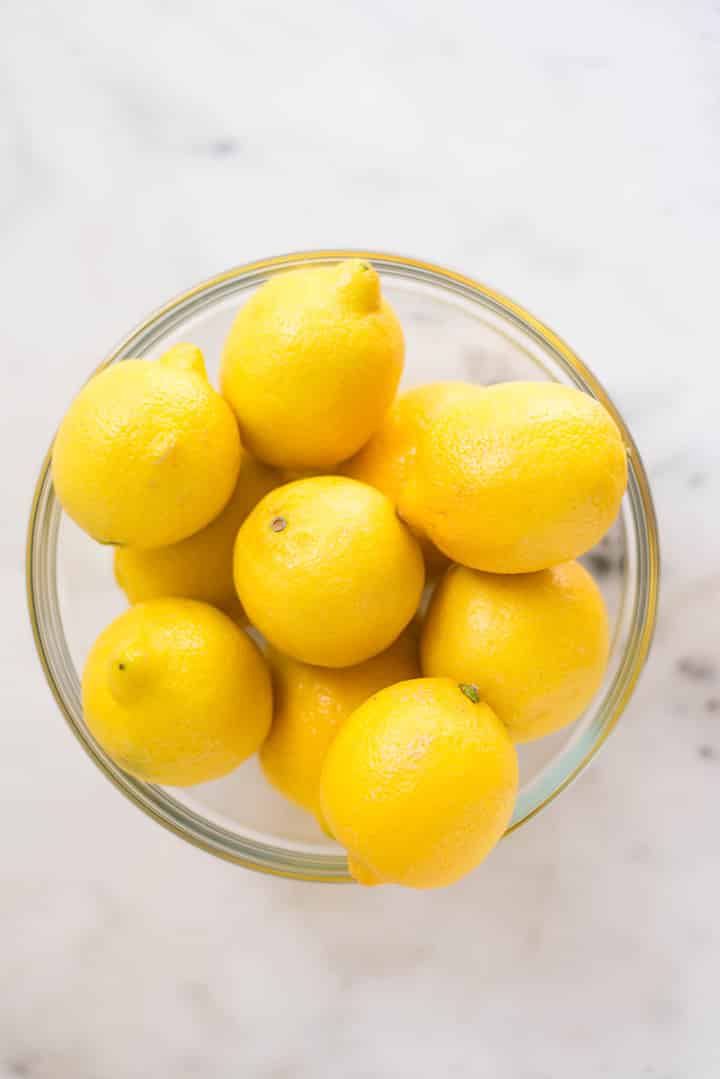 An overhead image of fresh lemons in a glass bowl on the kitchen counter for the Easy Homemade Lemonade.
