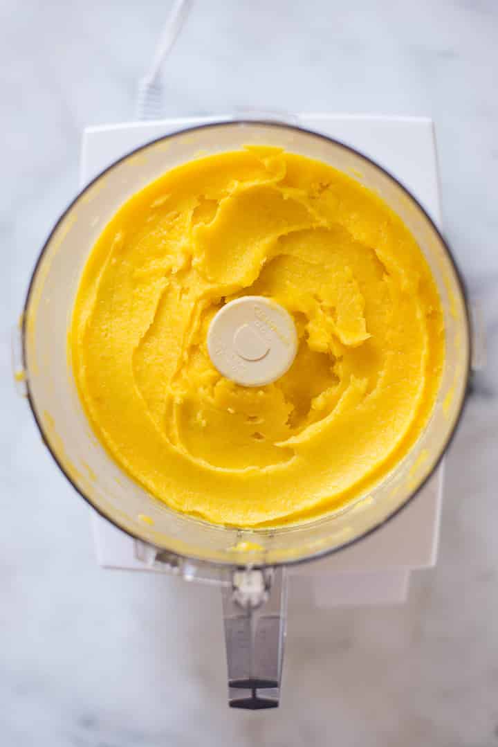 An overhead image of a food processor with mango puree made from frozen diced mango and lime juice for the Mango Sorbet.