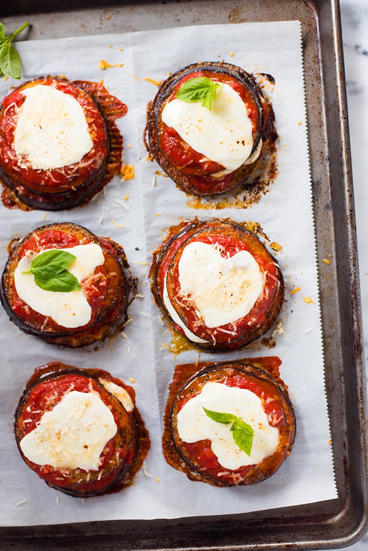 An overhead image of a baking sheet with cooked Baked Eggplant Parmesan made with roasted eggplant, homemade tomato sauce, mozzarella and grated parmesan.