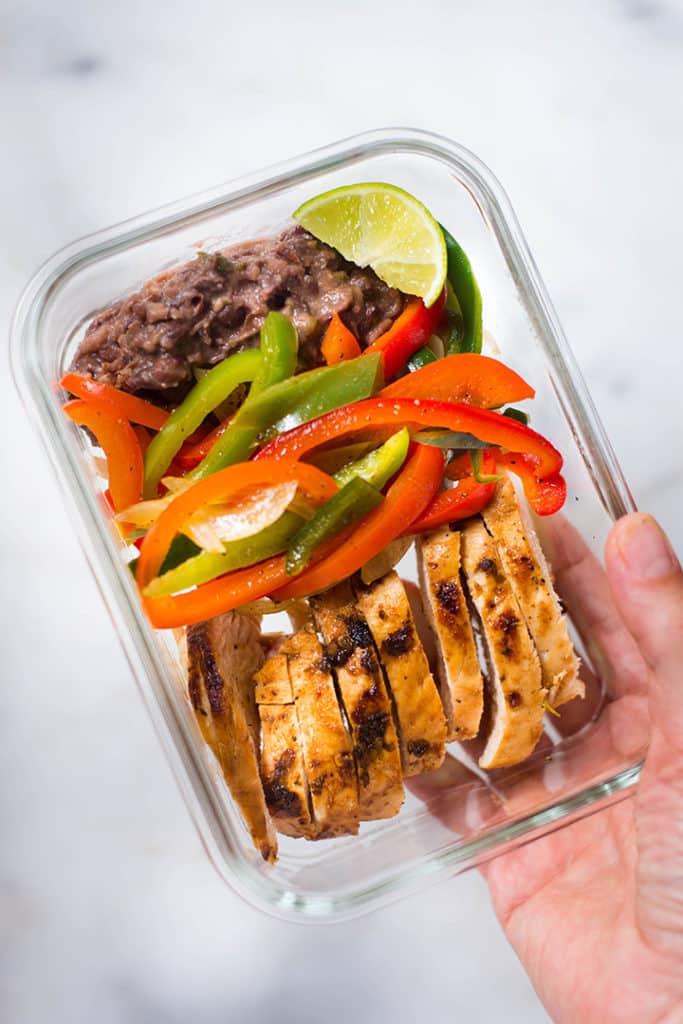 An overhead image of a meal prep container with Healthy Chicken Fajitas made with Fajita Chicken, Fajita Bell Peppers and Lime & Cilantro Black Beans ready to be stored in the fridge.