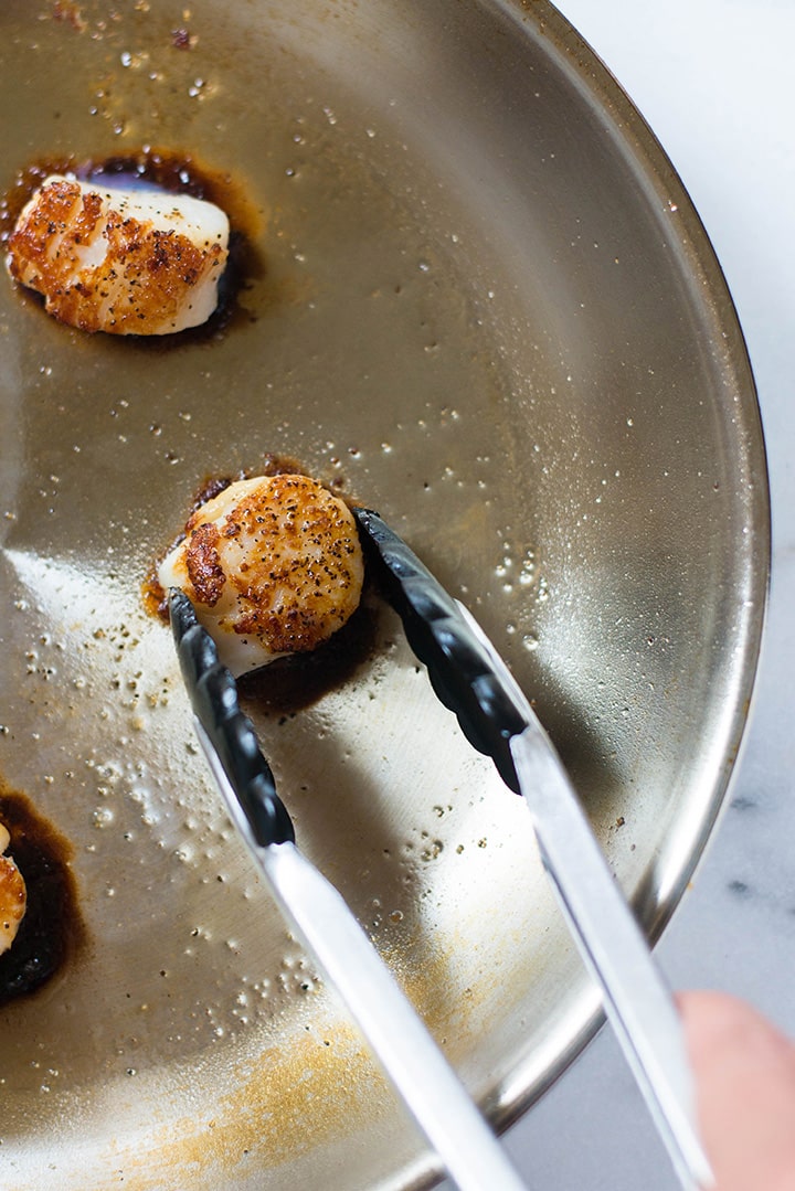 Close-up of searing scallops in the pan until they are browned nicely.