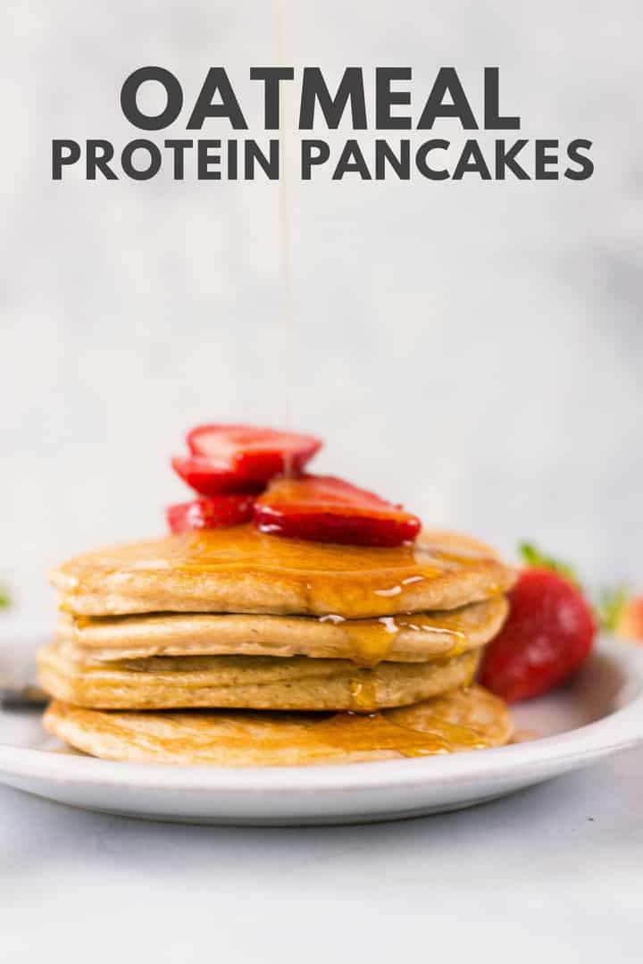 A side image of a stack of Oatmeal Protein Pancakes made with egg whites, uncooked rolled oats, protein powder, pure maple syrup and ground cinnamon, topped with fresh strawberries and drizzled with pure maple syrup.