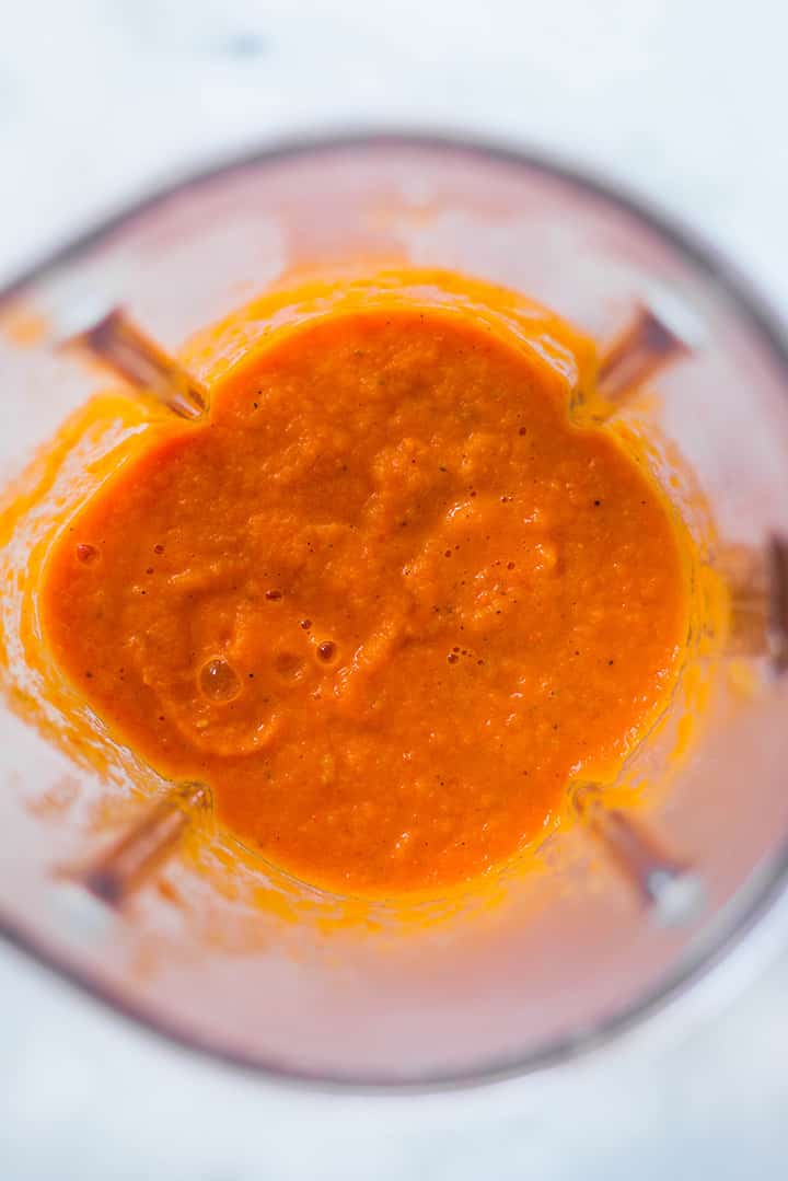 An overhead image of a blender with Roasted Tomato Sauce made with roma tomatoes, garlic, yellow onion, carrot, olive oil, basil, salt and pepper.