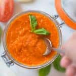 A close up image of Roasted Tomato Sauce in a glass jar, made with roma tomatoes, garlic, yellow onion, carrot, olive oil, basil, salt and black pepper.