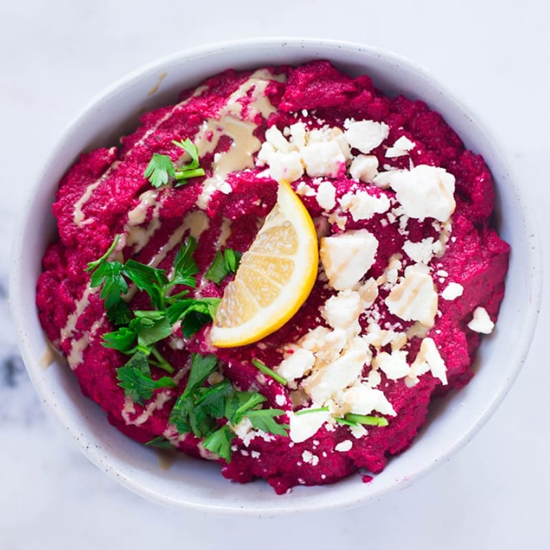 Overhead view of a bowl of pink hummus made from beets, which makes a great appetizer or a healthy snack .