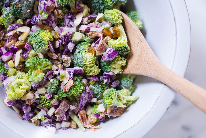 The Healthy Broccoli Salad with Greek Yogurt Dressing after all the ingredients have been mixed together with a wooden spoon. 
