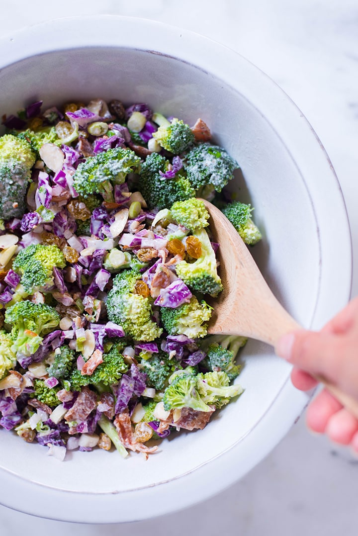 A close up view of a white bowl containing Healthy Broccoli Salad with Greek Yogurt Dressing, ready to eat as an healthy meal.