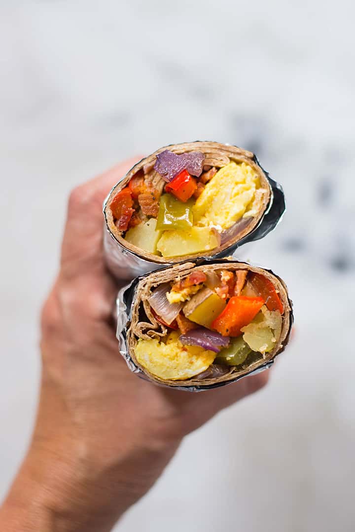 A close up of two Make Ahead Frozen Breakfast Burritos in someone's hand. The breakfast burritos are ready to be eaten.