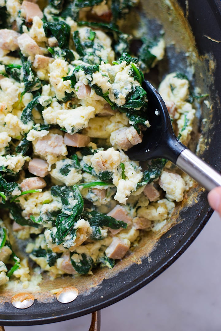 Close up of breakfast meal prep that includes egg whites scramble with ham and spinach in the skillet. 