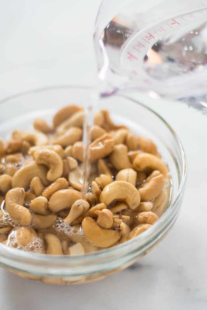 Raw cashews in a bowl being soaked with hot boiling water.