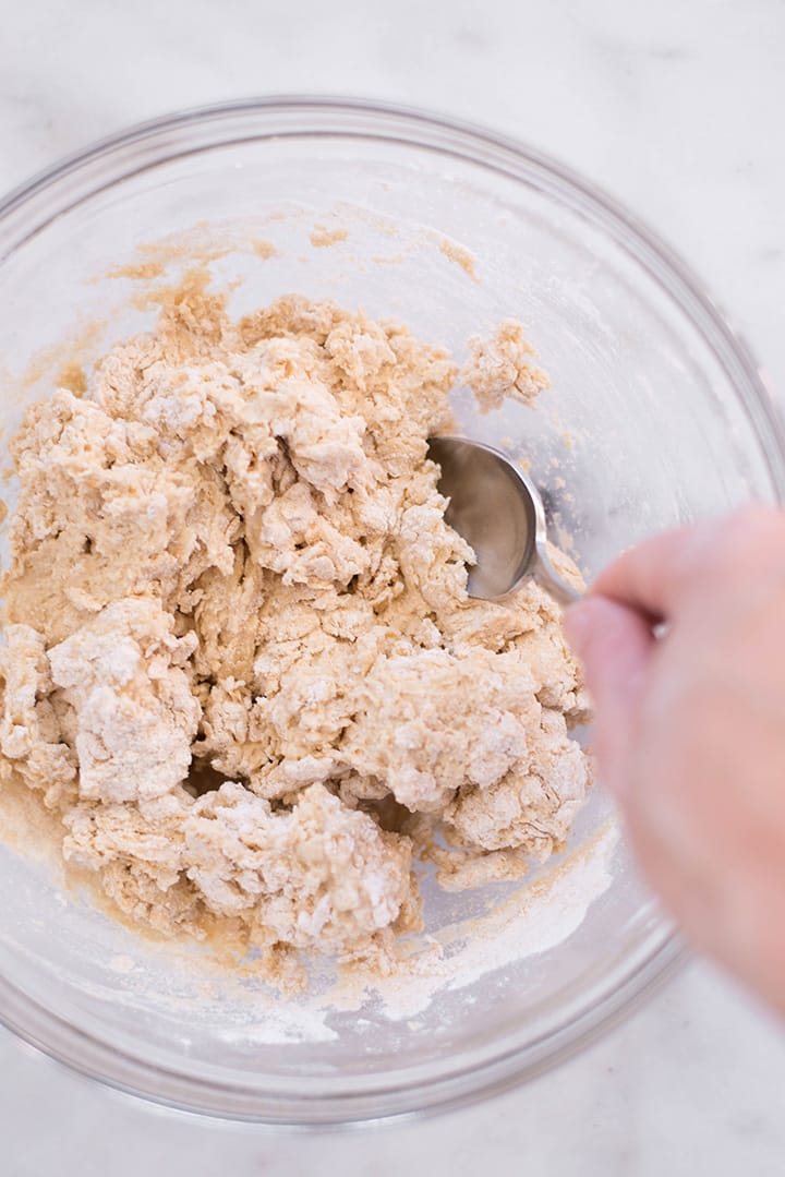 Mixing the ingredients for the whole wheat pizza dough including whole wheat pastry flour, baking powder, sea salt and olive oil in a mixing bowl.