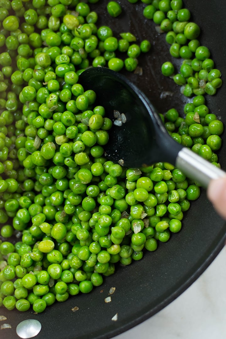 Overhead image of cooking the peas in a skillet, be served as a side dish for the Easy Meal Prep Salisbury Steak.