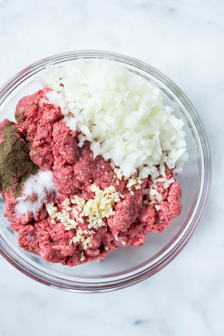 Ingredients for Easy Meal Prep Salisbury Steak including minced beef, garlic, salt, and pepper in a mixing bowl.
