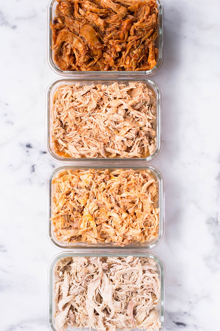 Close up overhead view of 4 types of shredded chicken, placed in 4 glass meal prep dishes according to flavor.