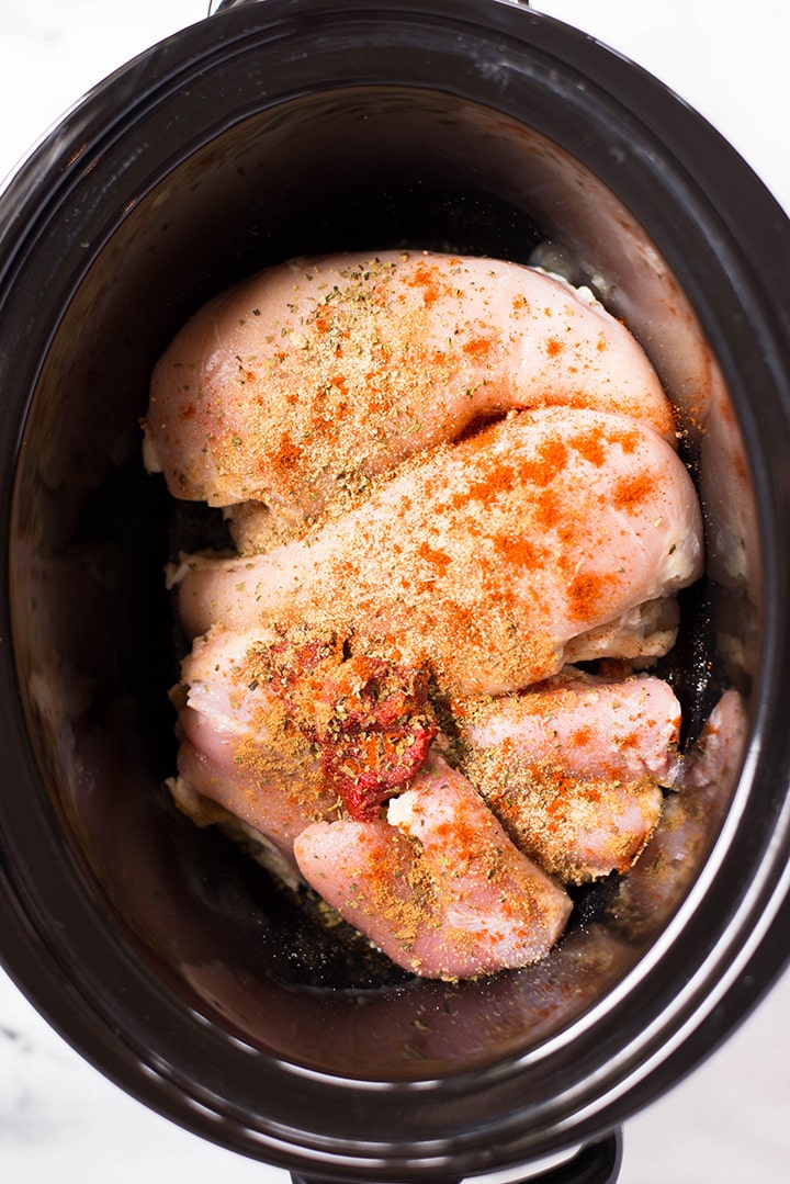 Making Slow Cooker Mexican Shredded Chicken. The chicken breasts and chicken thighs are tossed with olive oil, tomato paste, and seasoned with sea salt, oregano, garlic powder, onion powder, cumin, cayenne pepper and lemon juice.