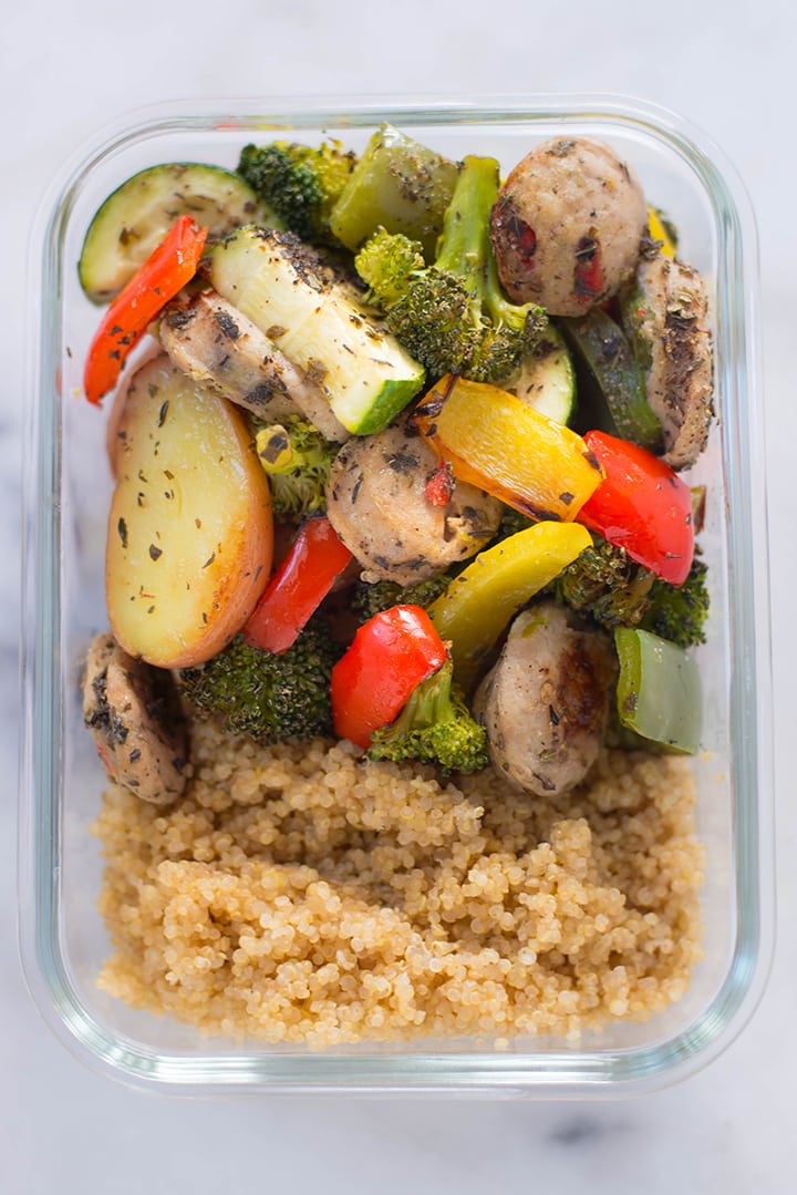 Close up view from the top of the meal prep container filled with quinoa, oven roasted veggies and sausage.