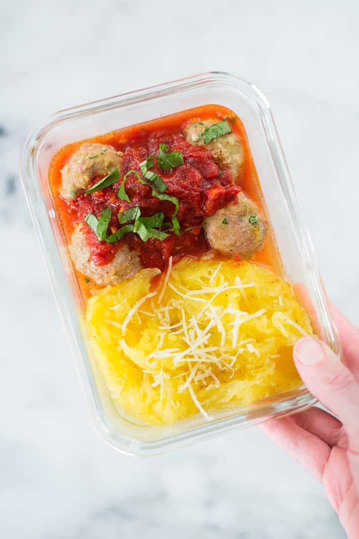 Lacey holding a meal prep container with Turkey Meatballs with Spaghetti Squash Noodles.