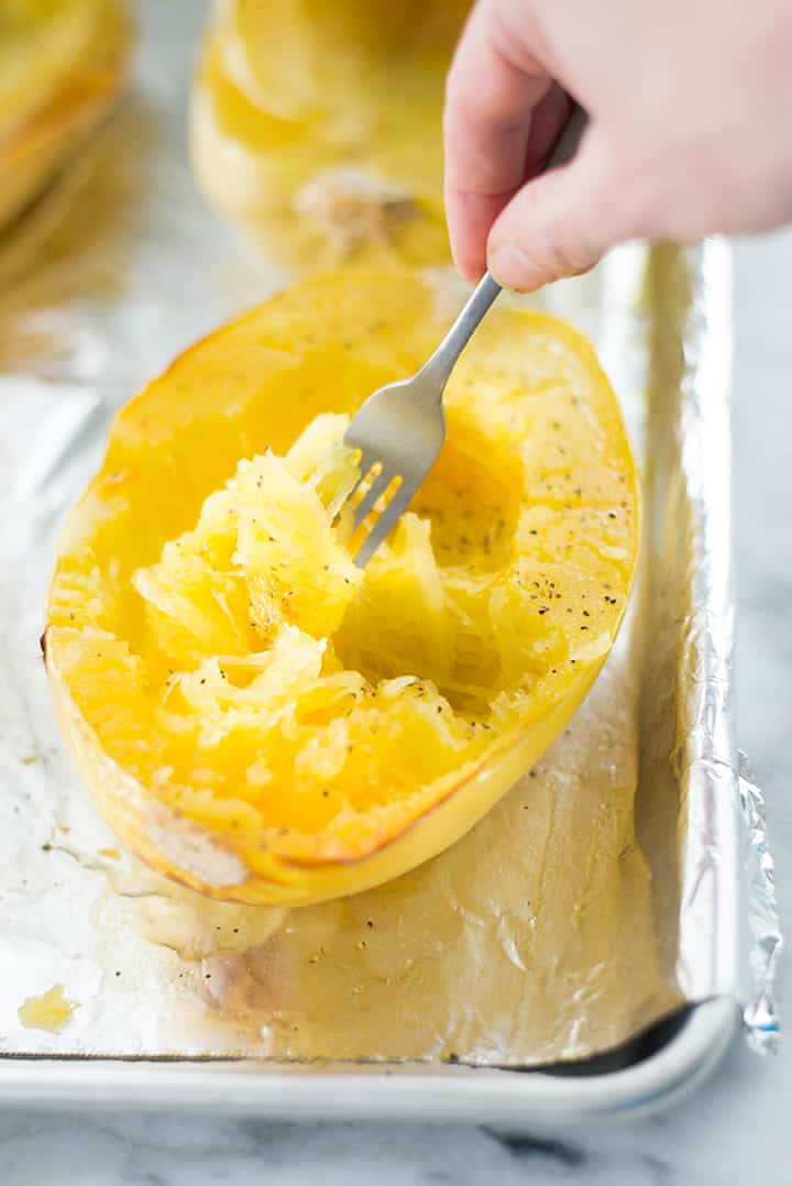 Making Spaghetti Squash Noodles by scraping baked squash with a fork.