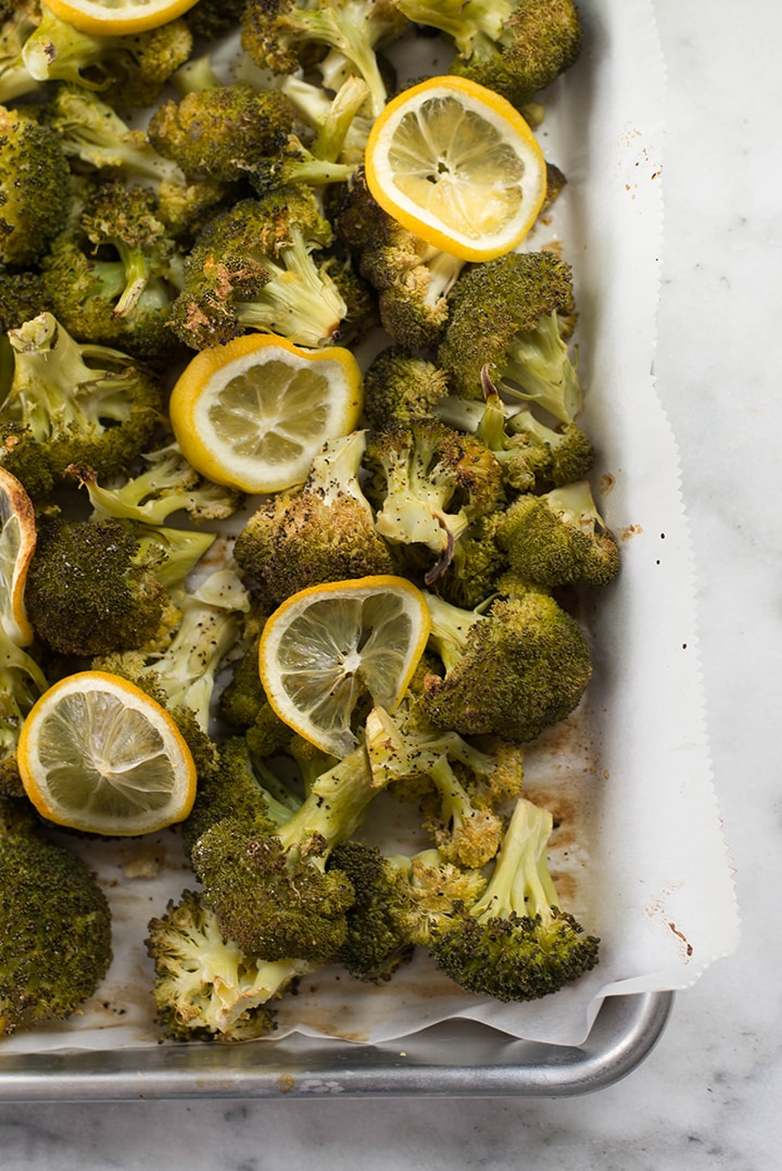 Top view of roasted broccoli on a baking sheet. The roasted broccoli was garnished with lemon slices.